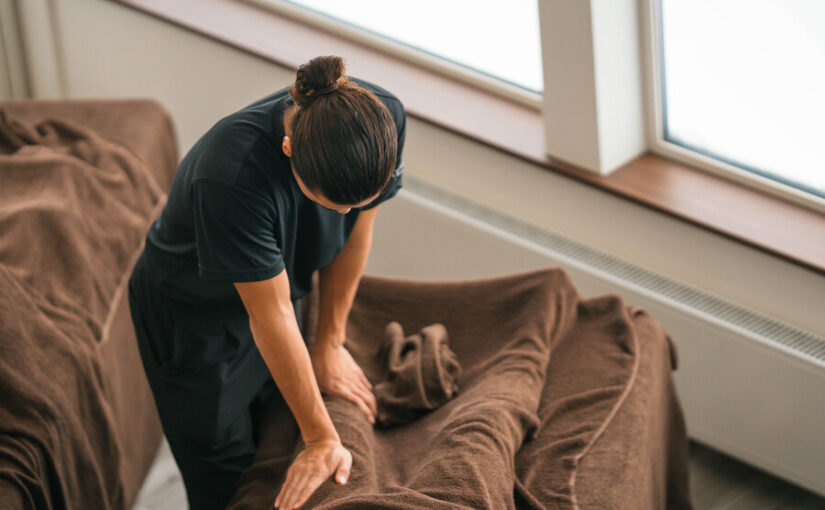 ニセコで体験できるドライマッサージ。施術ベッドに横たわる顧客に対し、タオル越しに指圧を行うセラピスト